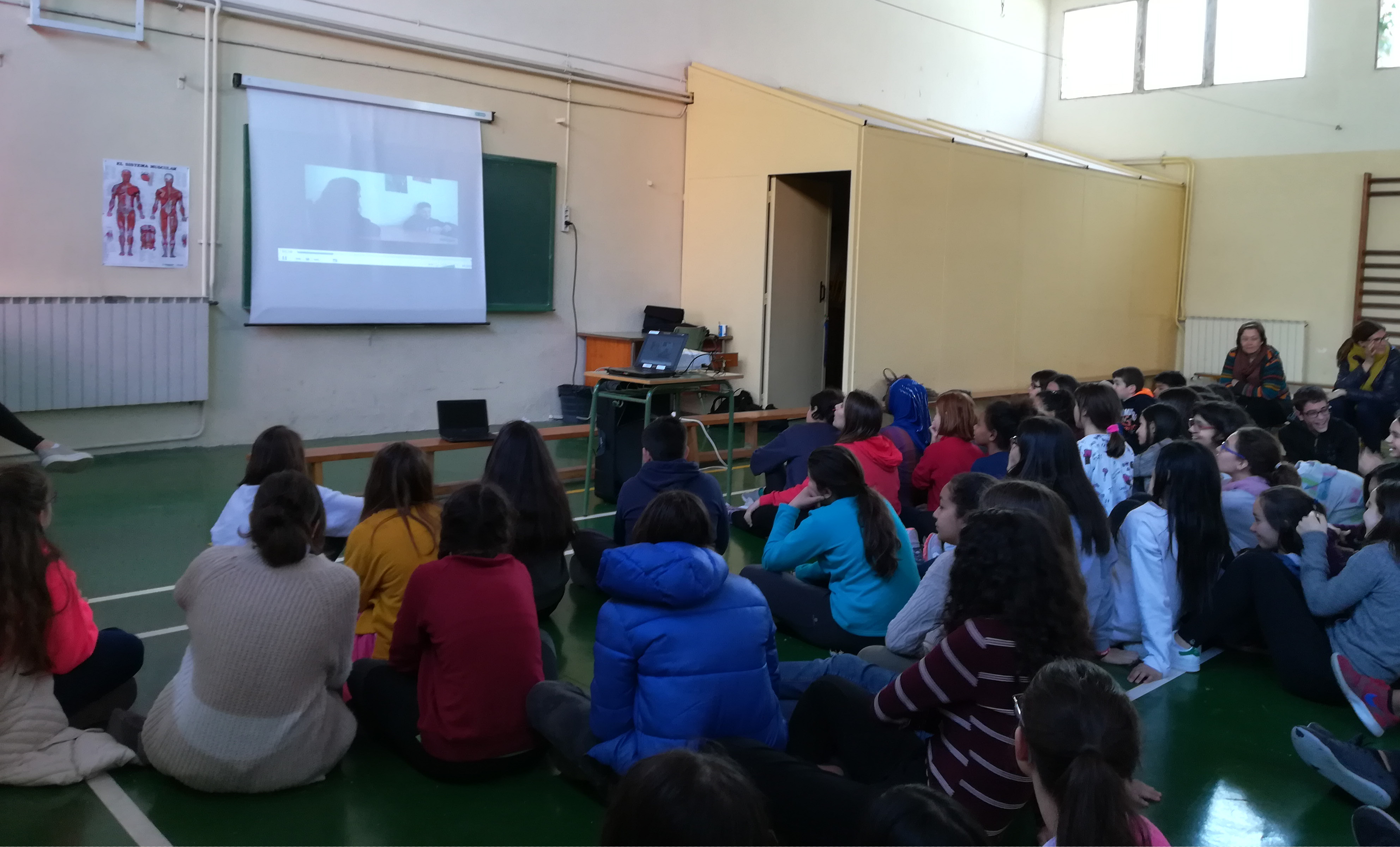 alumnes asseguts mirant els vídeos creats pels companys en un projector